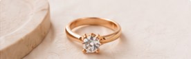 A rose-gold solitaire engagement ring on cream silk