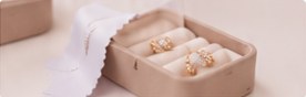 Diamond studs and rings arranged in a cream jewellery box