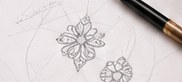 Pencil sketches of floral pendant designs on a drafting sheet